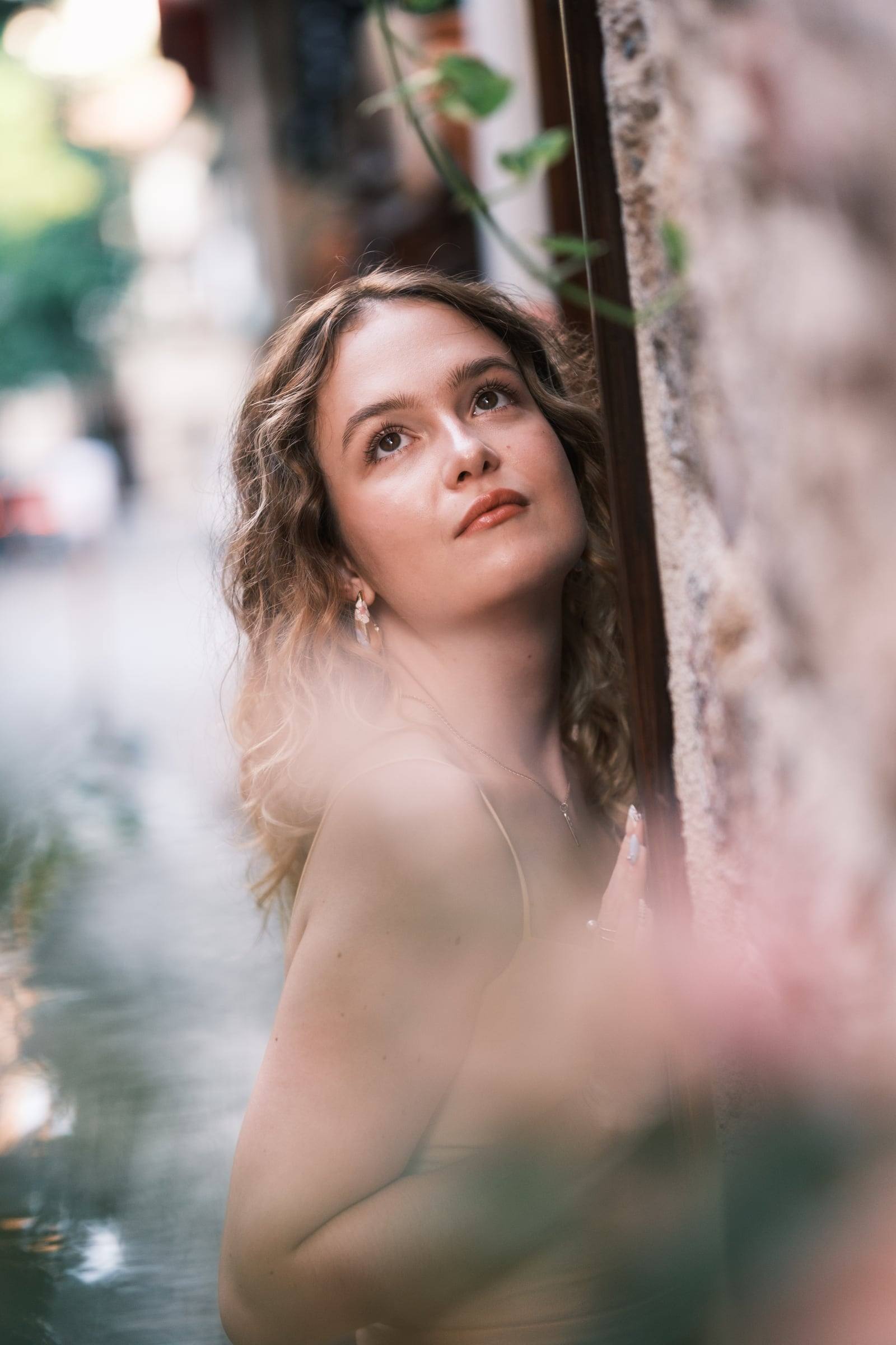 Young woman leaning on an old-town wall among flowers