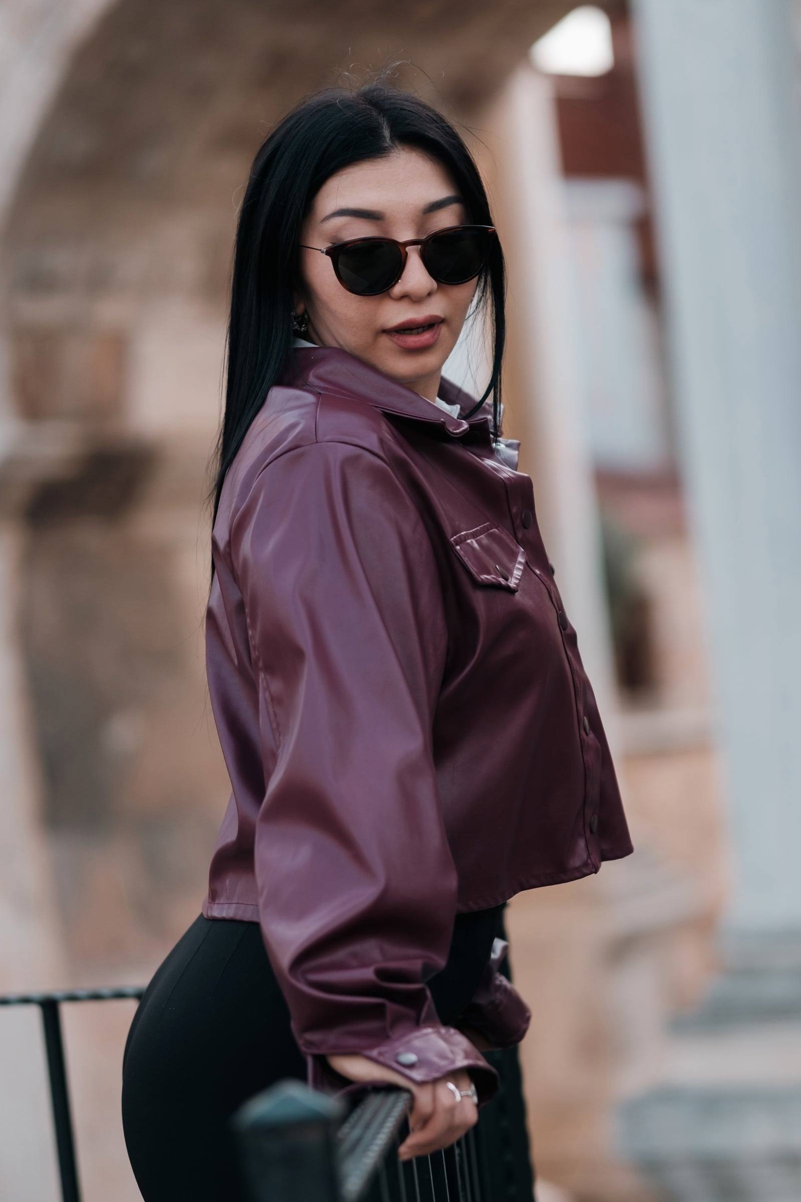 Woman in a burgundy leather jacket and sunglasses at Hadrian's Gate