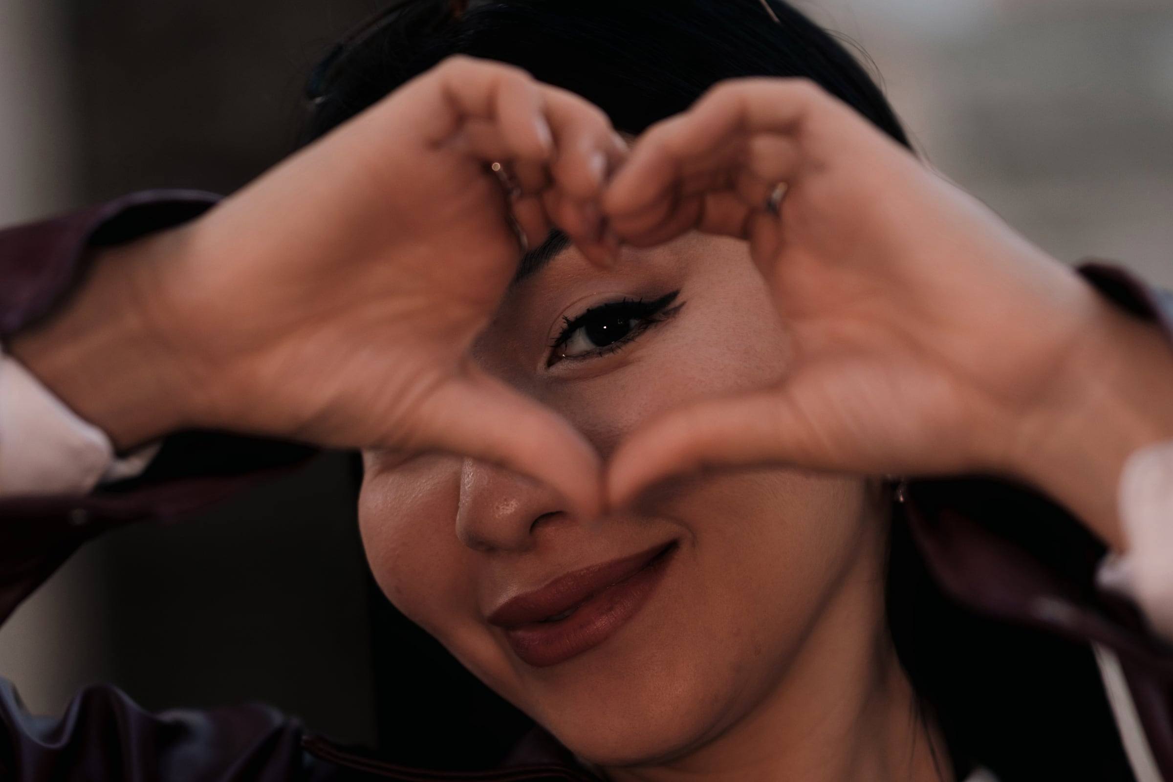 Woman smiling and making a heart shape with her hands