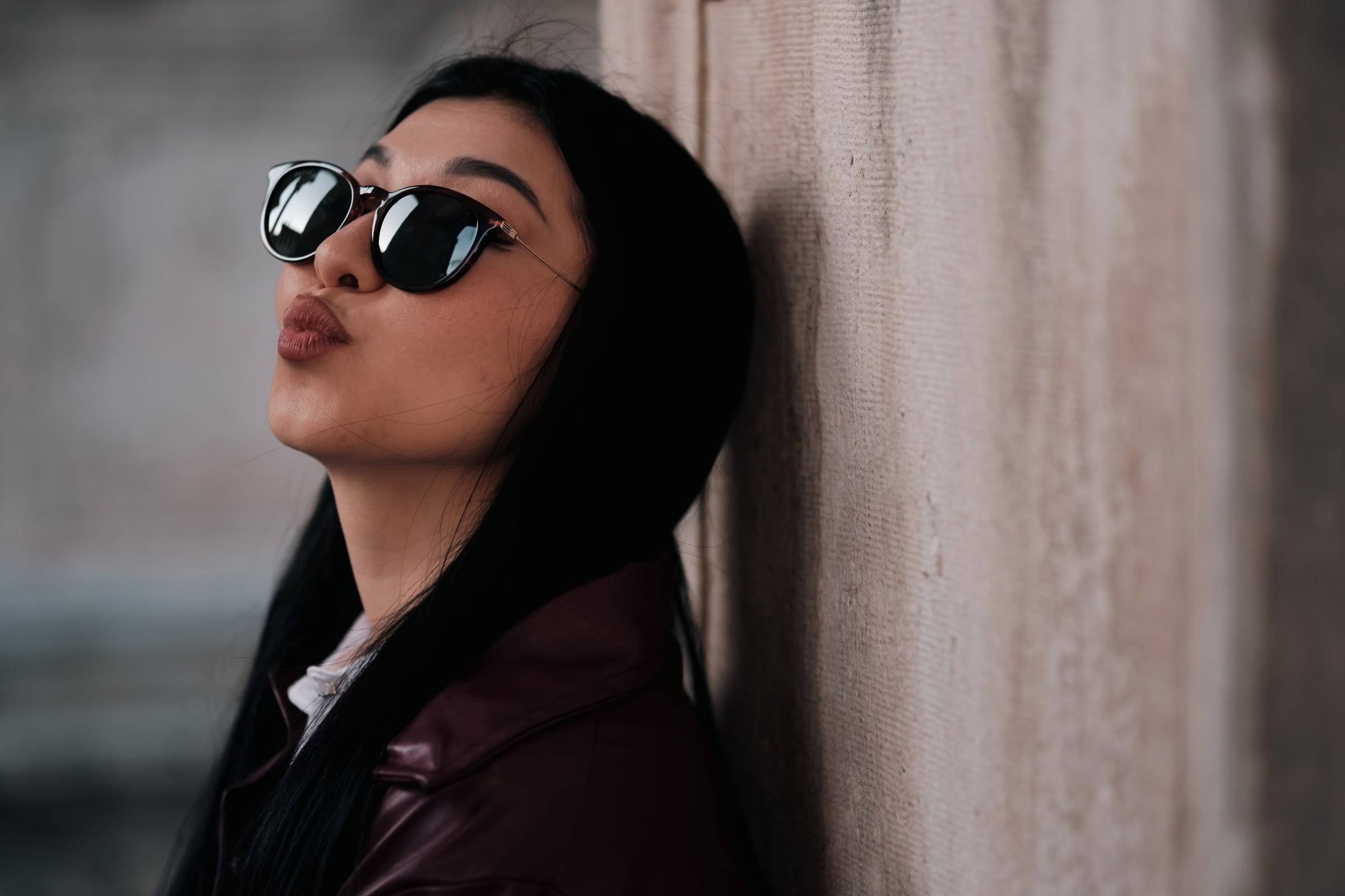 Woman in sunglasses against a stone wall