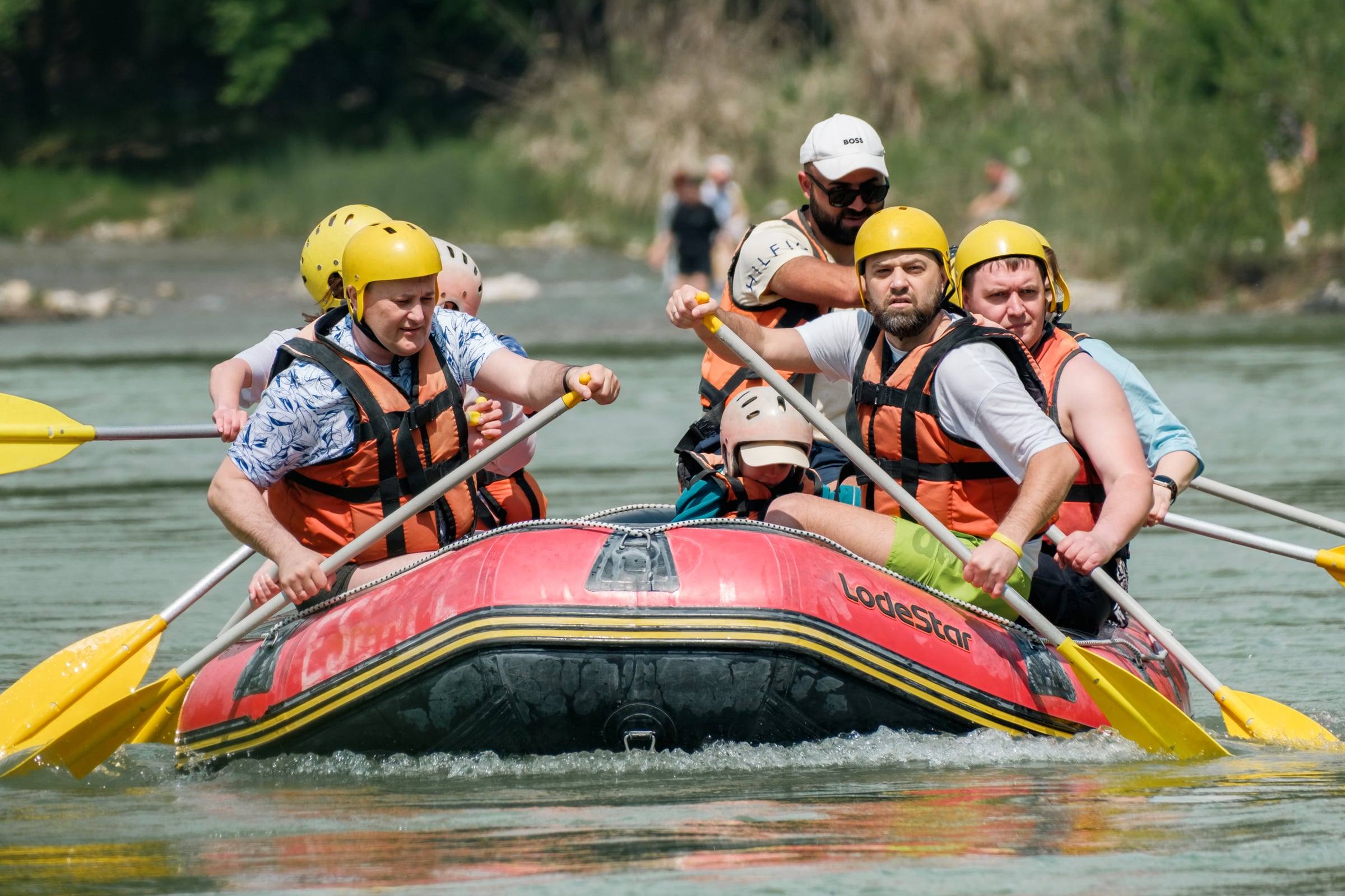 Team rafting down a river in helmets and life jackets