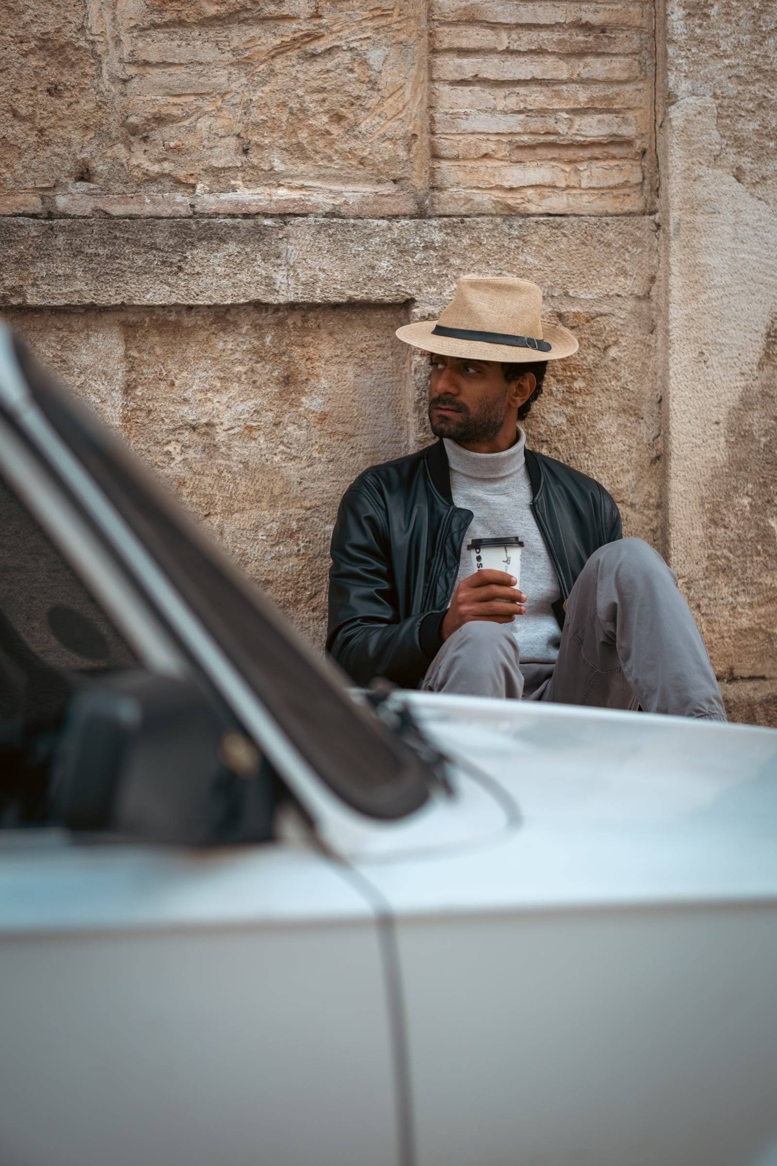 Man in a hat leaning on a vintage car