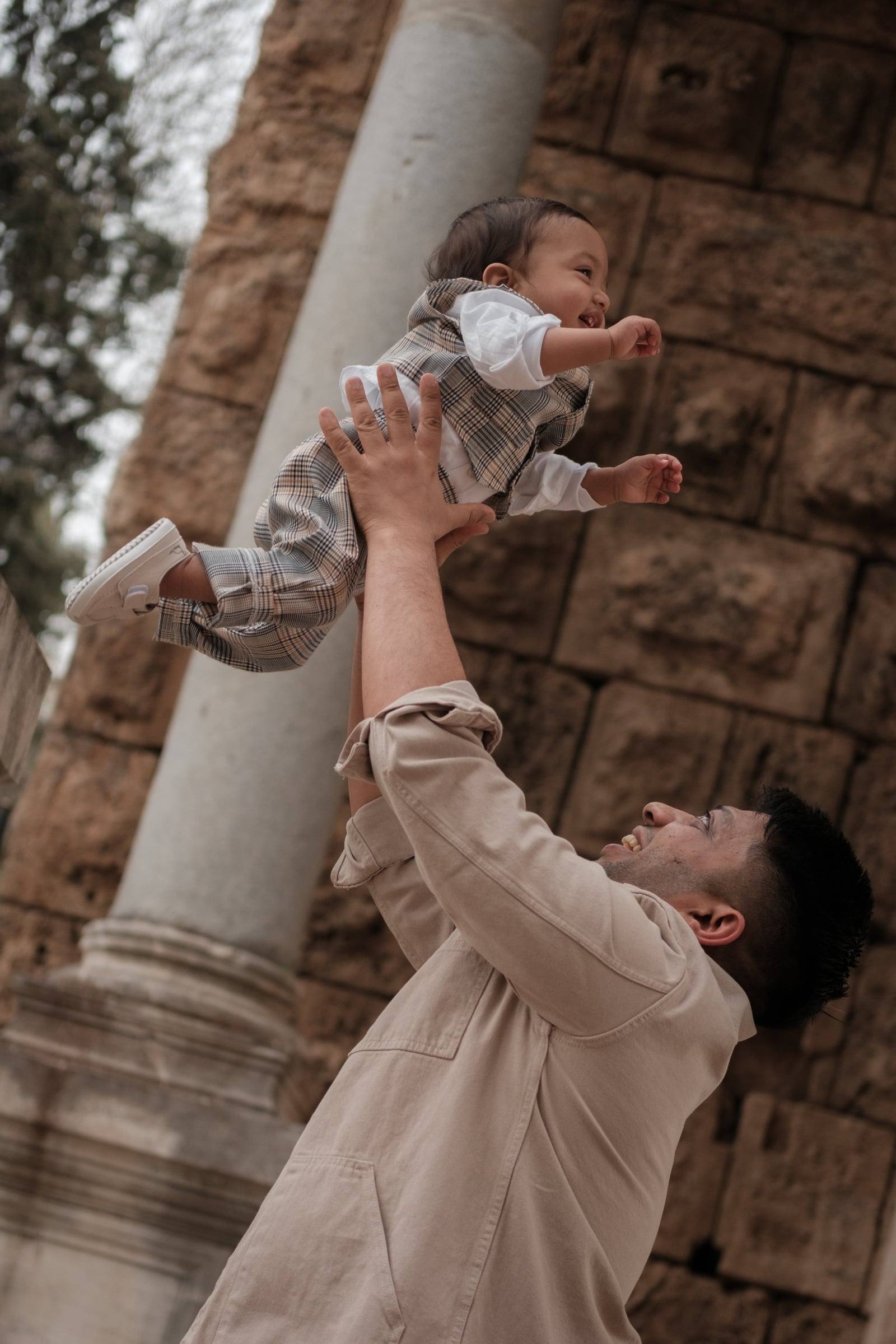 Father lifting his baby son up beside an ancient column