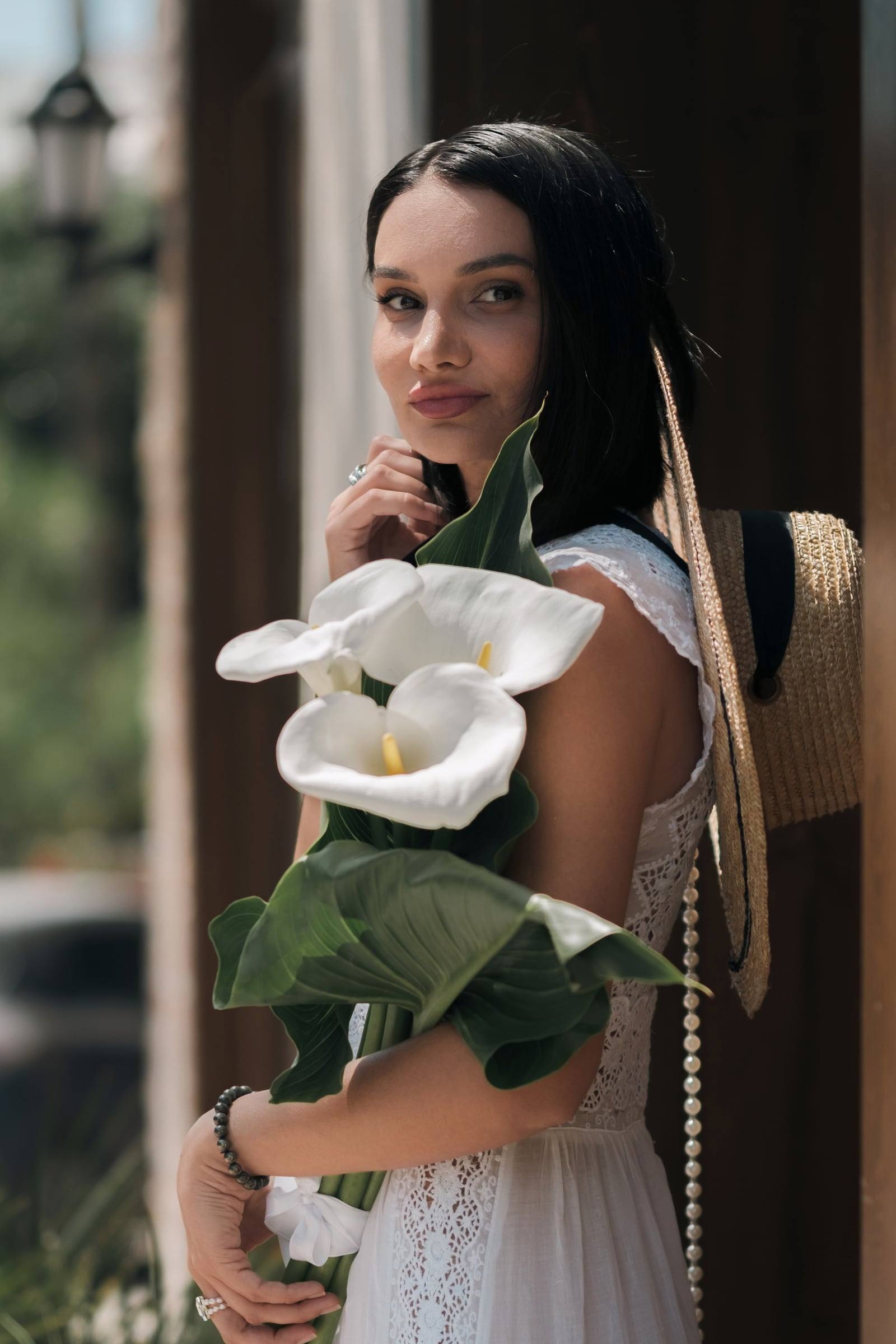 Woman holding calla lilies in a doorway