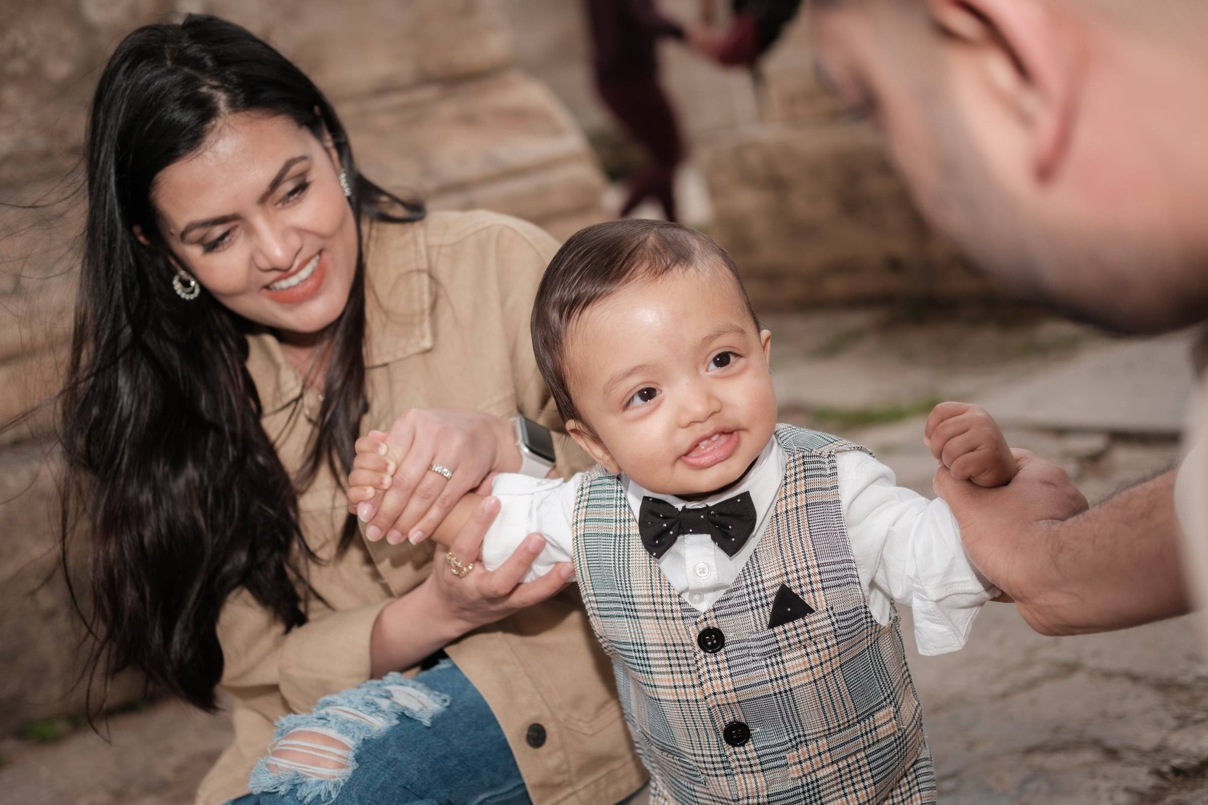 Smiling baby boy in a bow tie with his mother