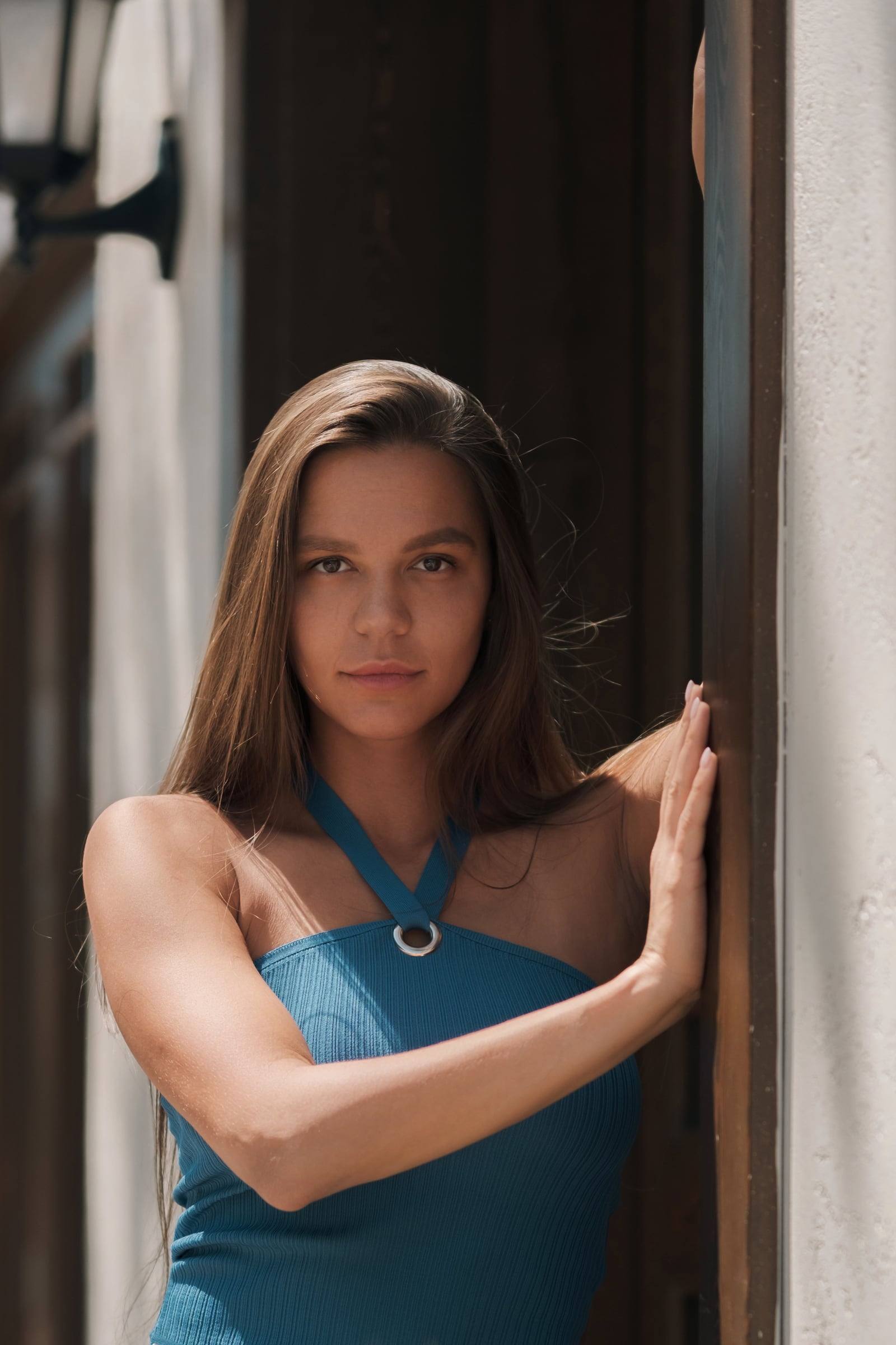 Woman in a blue top leaning in a wooden doorway