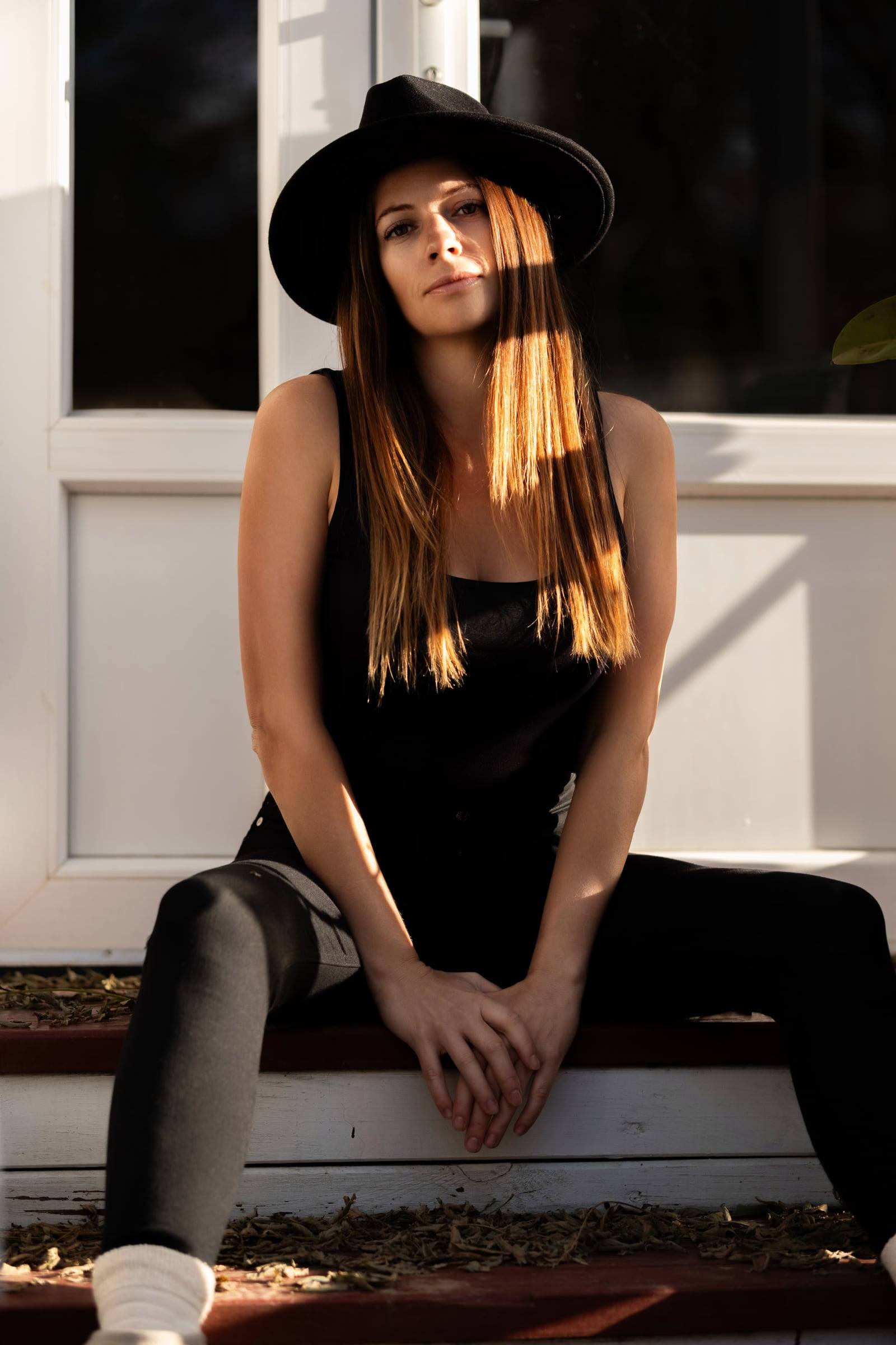 Woman in a black hat sitting on a doorstep