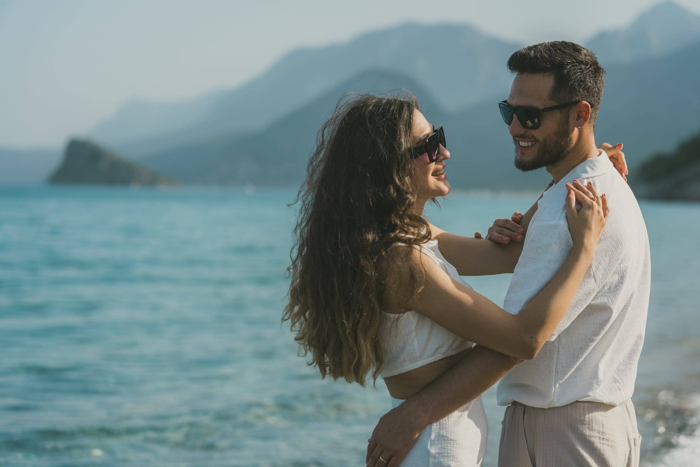 Couple dancing in the sea with mountains behind