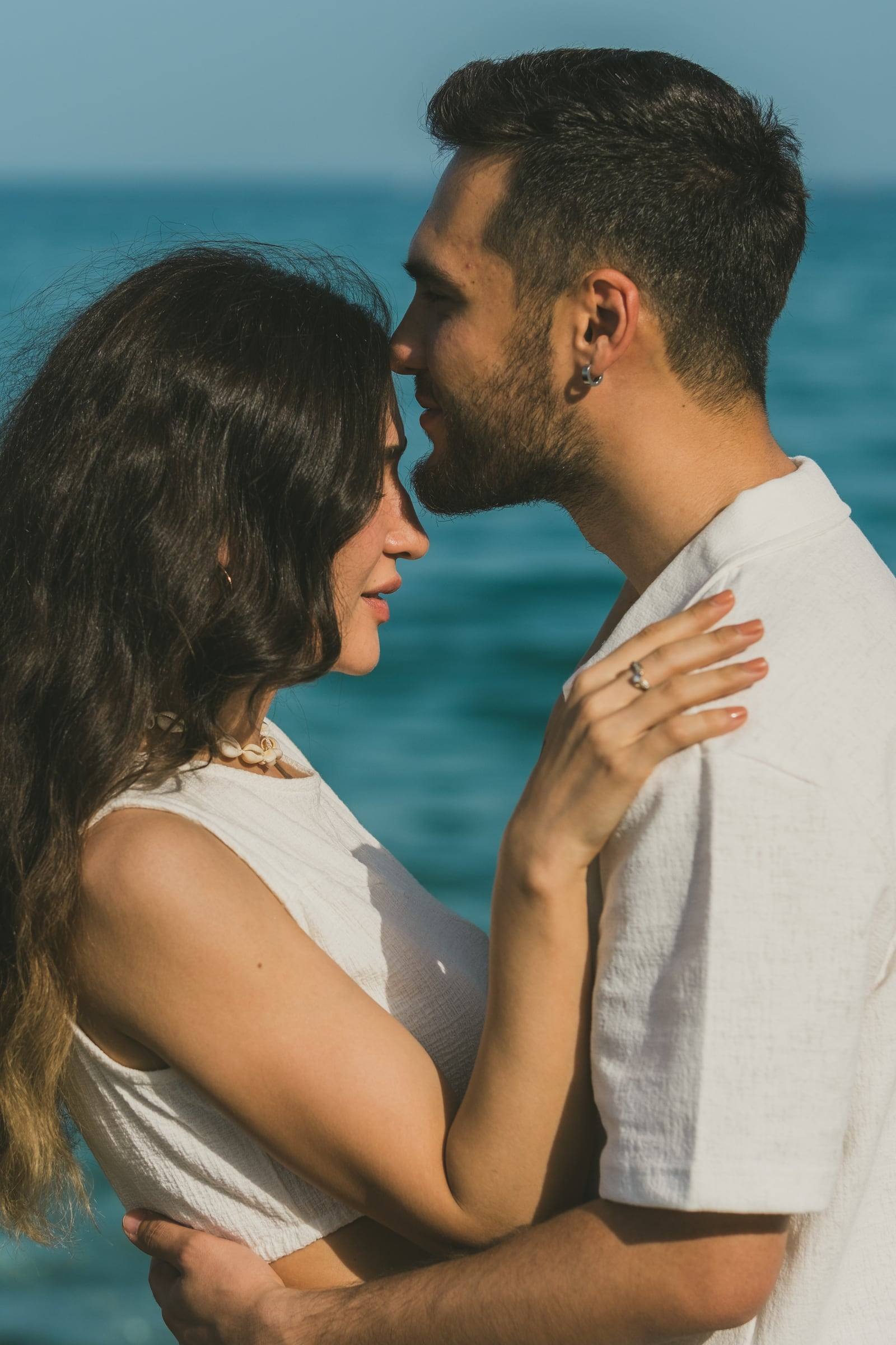 Couple touching foreheads against the blue sea