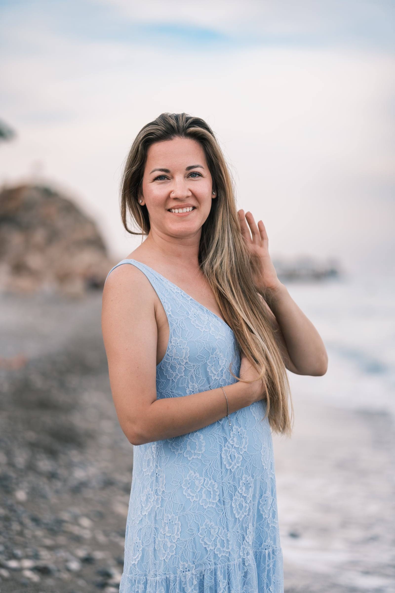 Smiling woman in a blue dress on the beach