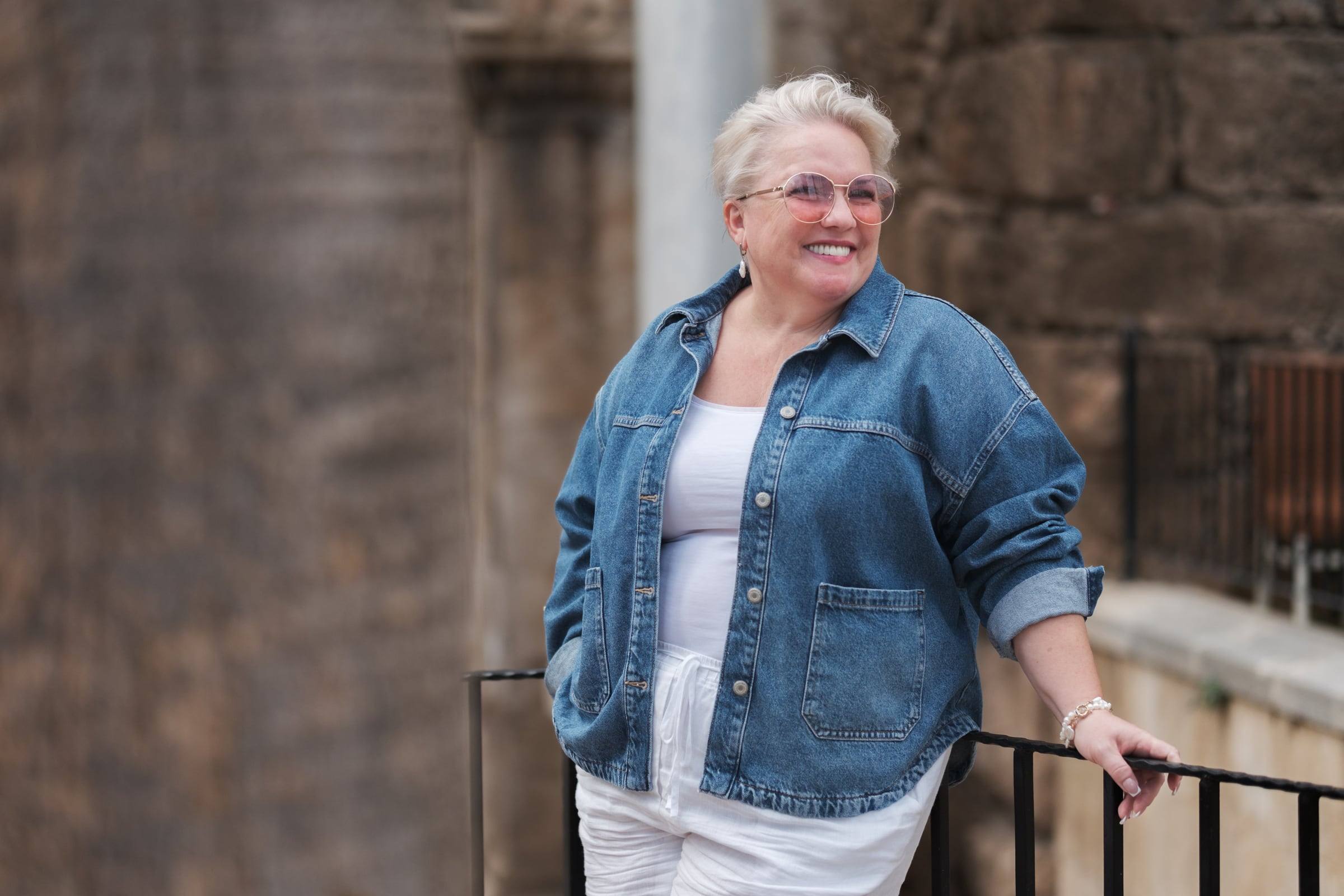 Smiling woman in a denim jacket by the railing of Hadrian's Gate