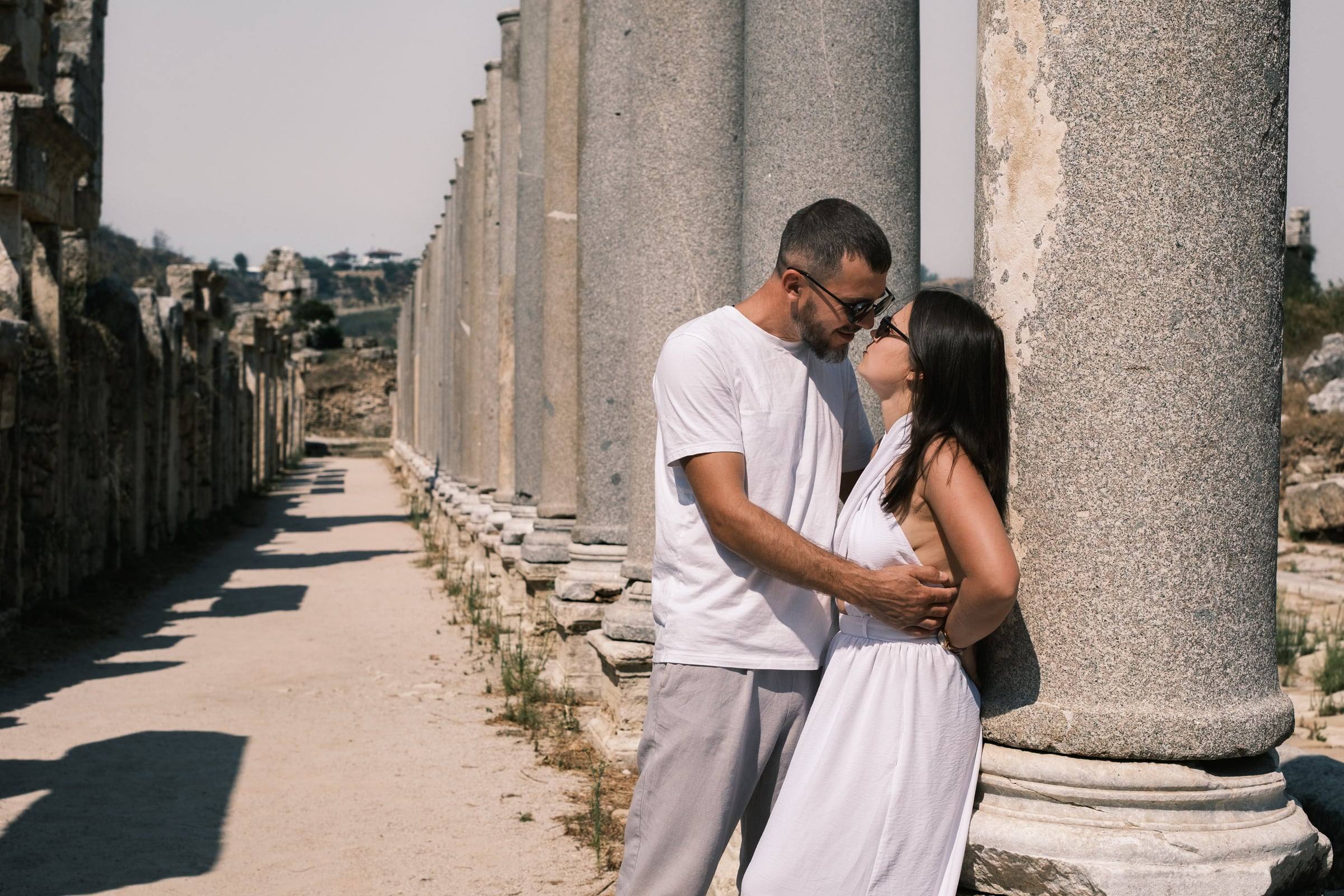 Couple embracing beside a long row of ancient columns