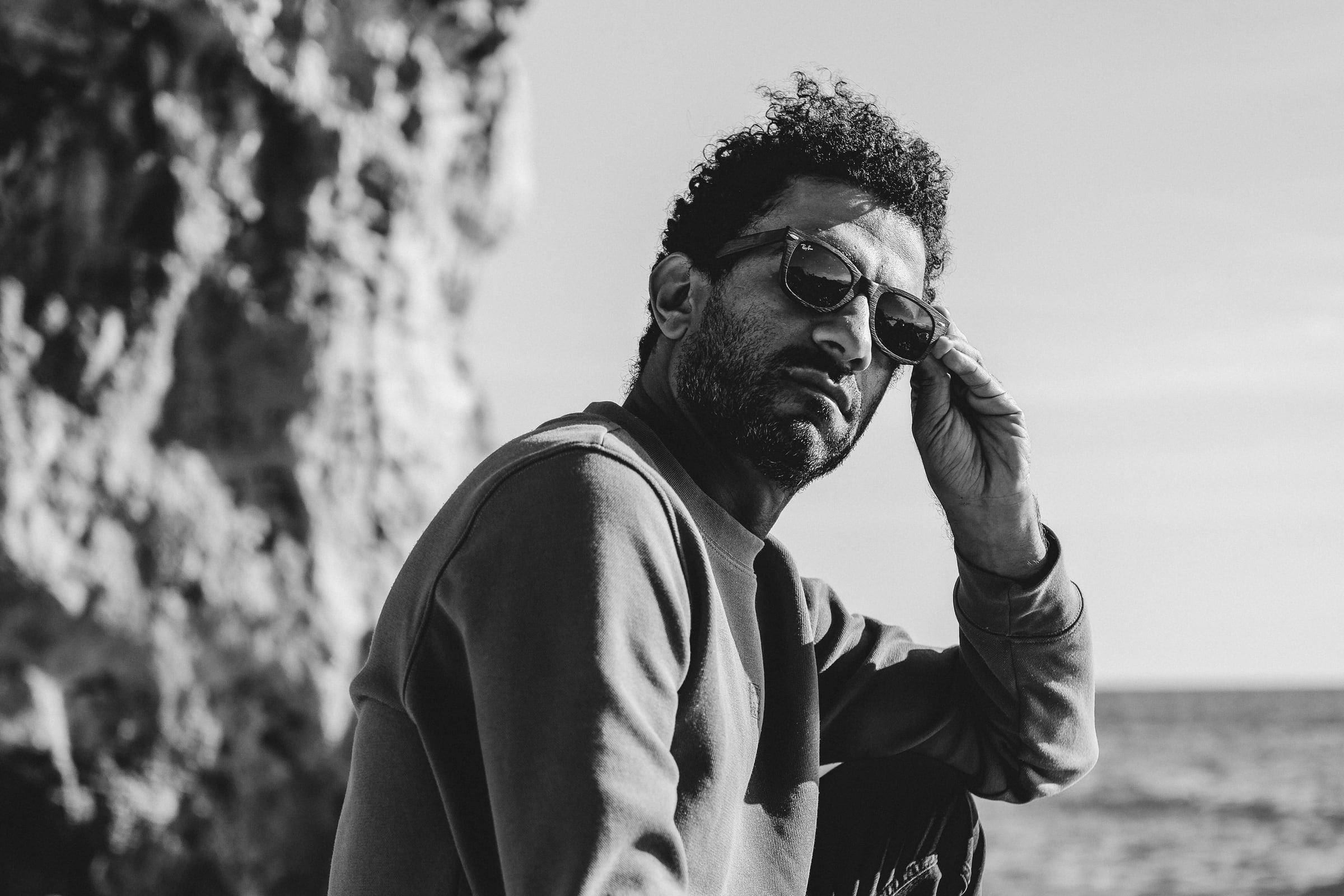 Black-and-white portrait of a man in sunglasses by the sea