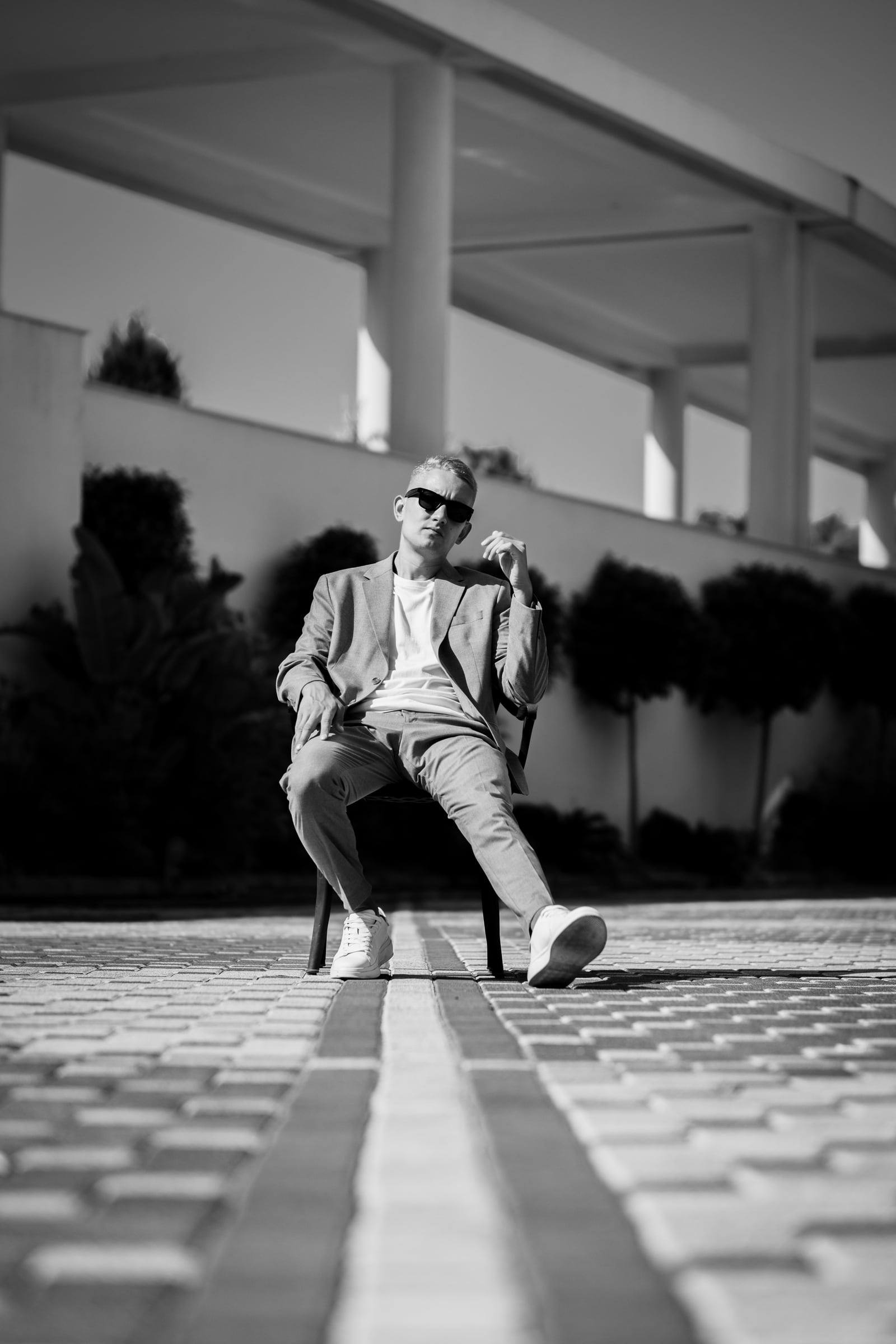 Black-and-white portrait of a man in a suit sitting on a paved terrace