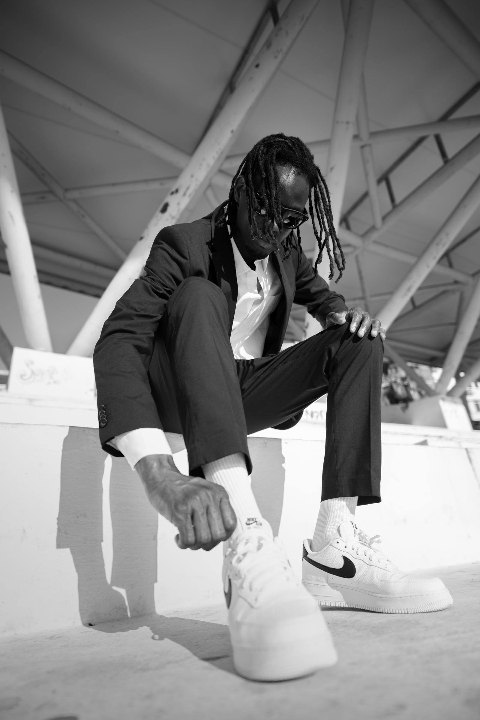 Black-and-white portrait of a man tying his sneakers