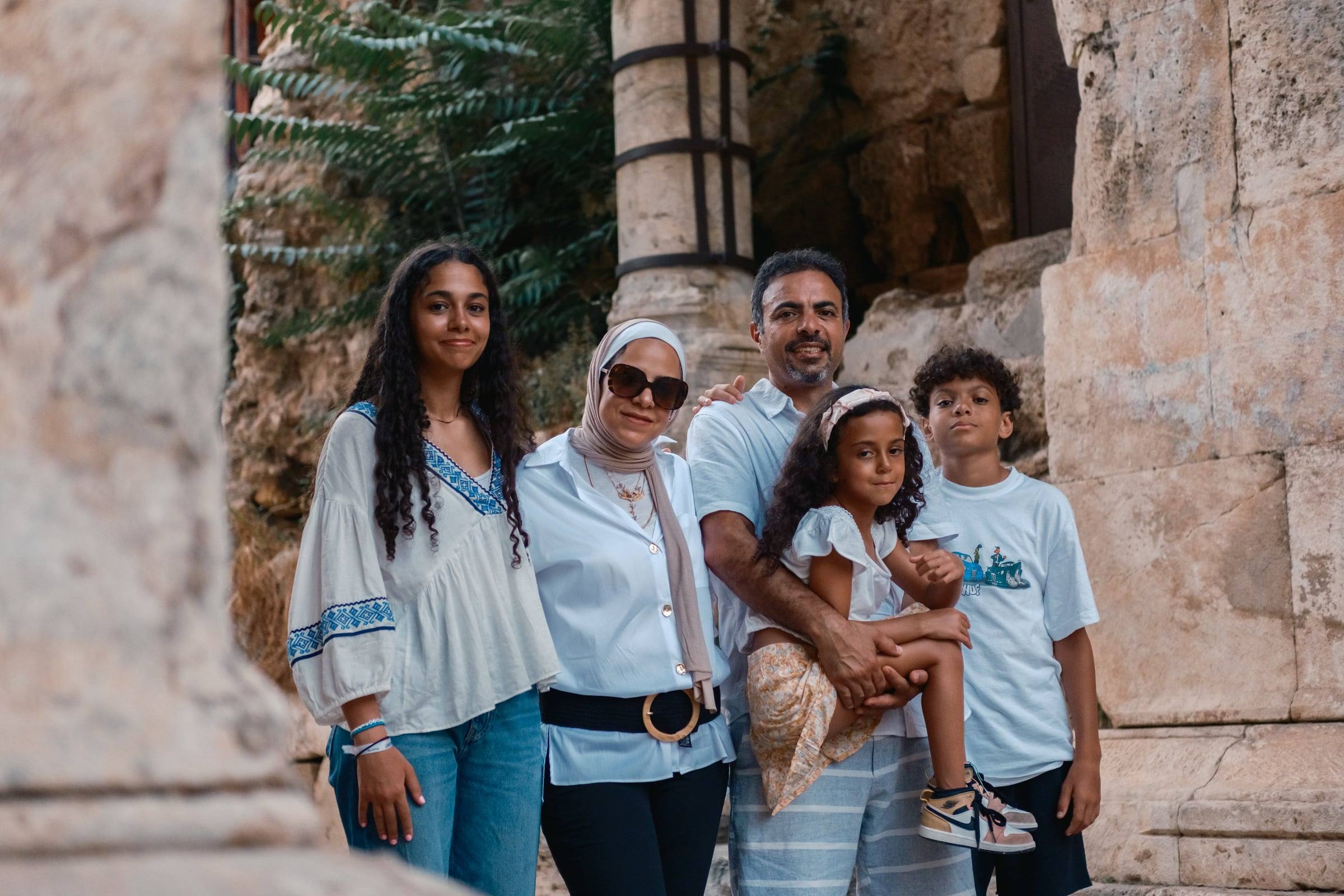 Family smiling together beside the ancient columns
